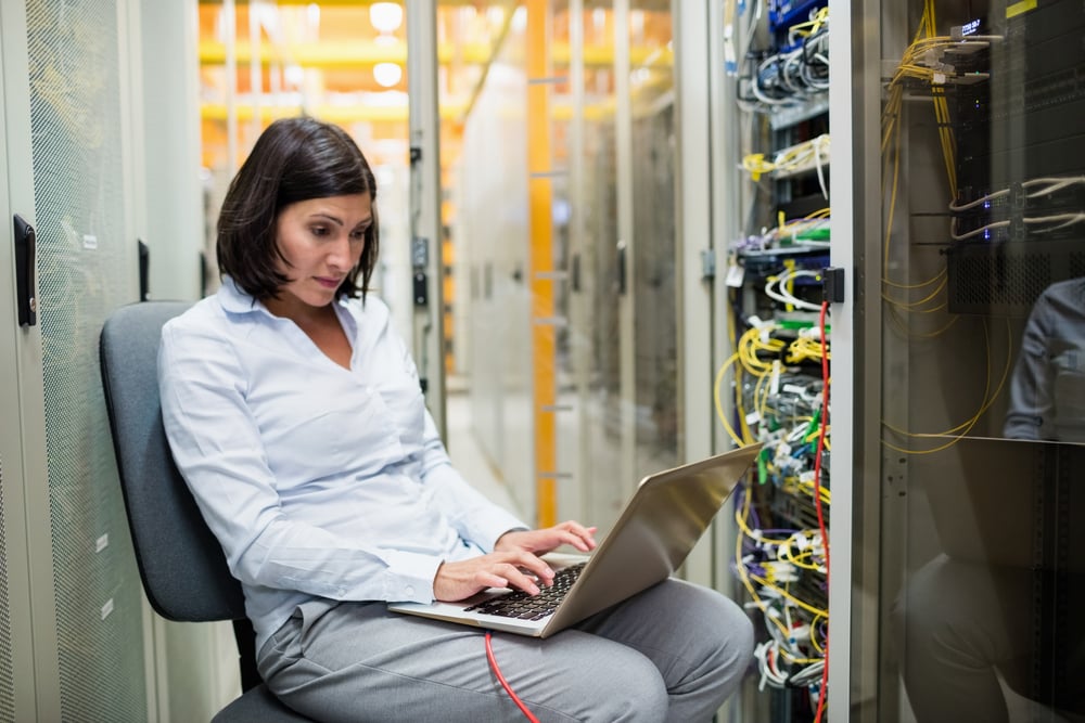 Attentive technician working on laptop in server room