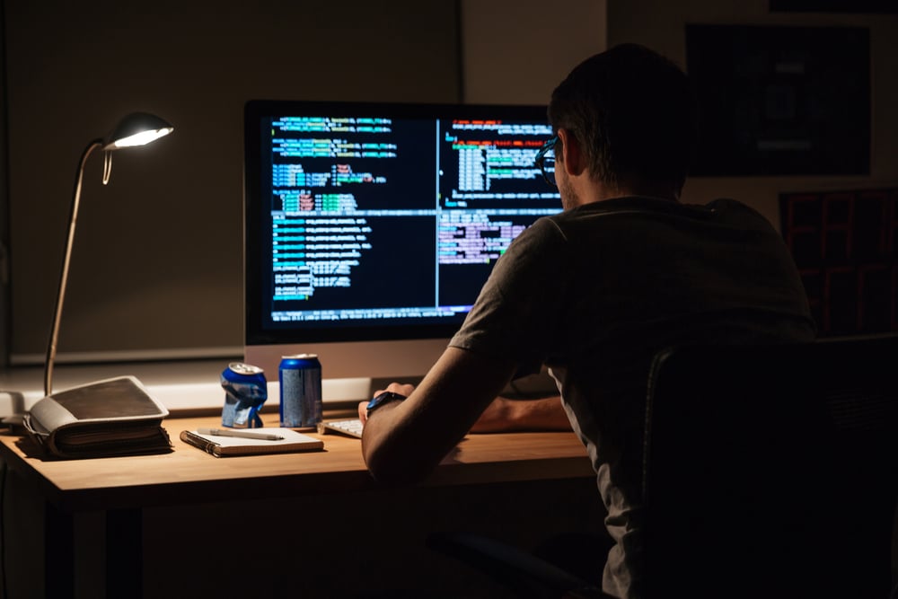 Back view of modern programmer sitting and writing code in dark room-2