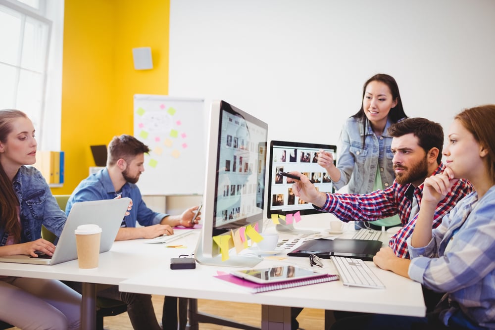 Businessman showing computer screen to coworkers in creative office-3