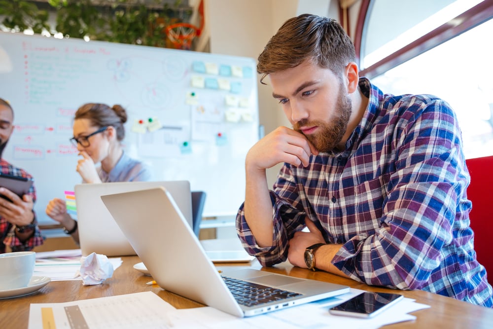 Concentrated bearded young man using laptop while his friends studying together-2