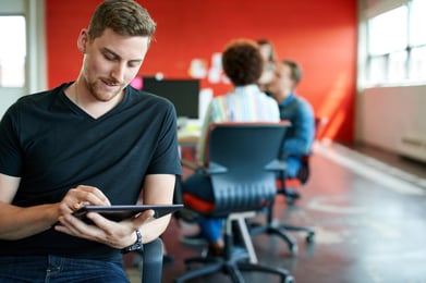 Confident male designer working on a digital tablet in red creative office space-1