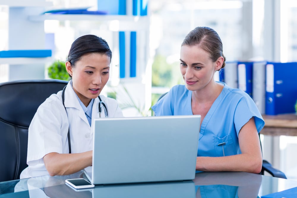 Doctor and nurse looking at laptop in medical office-1