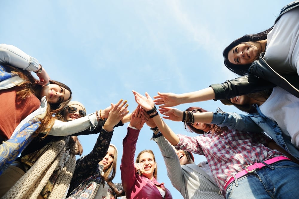 Happy teen girls having good fun time outdoors and posing in circle with copy space