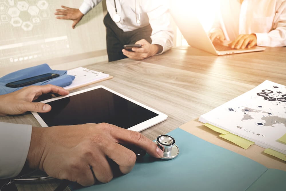 Medicine doctor hand working with modern computer and digital pro tablet with blank screen with his team on wooden desk as medical concept 2