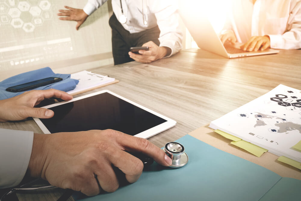 Medicine doctor hand working with modern computer and digital pro tablet with blank screen with his team on wooden desk as medical concept 2