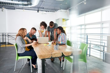 Multi ethnic group of succesful creative business people using a laptop during candid meeting-3