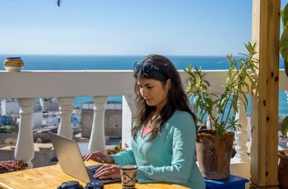 Girl working on her laptop with sea view in the background