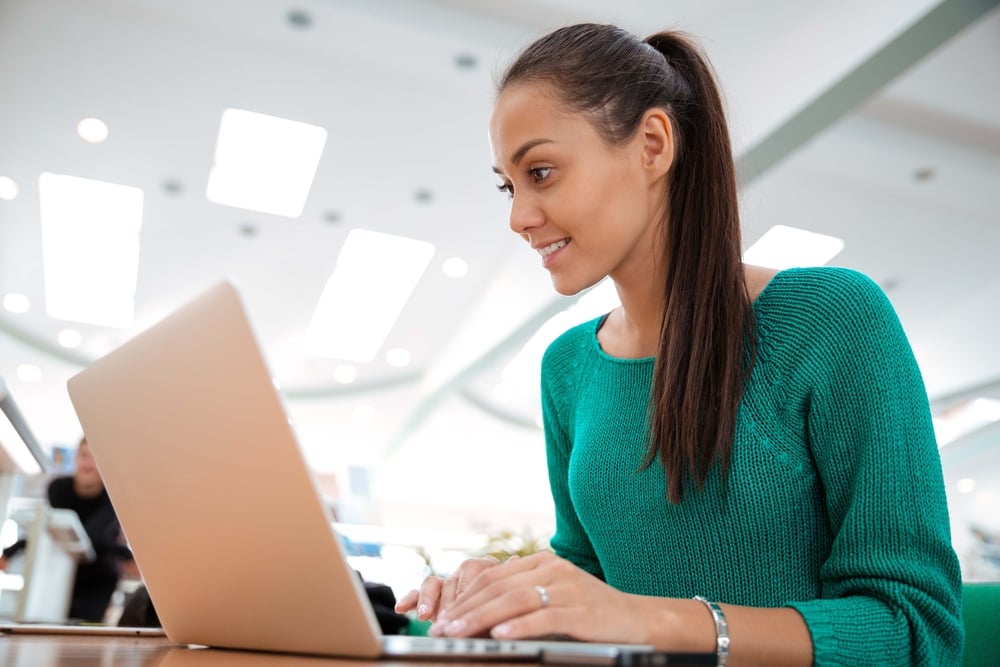 Portrait of a happy female student using laptop computer in university-3