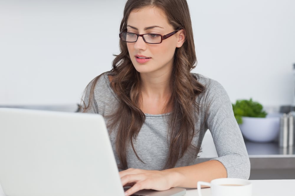 Pretty woman typing on her laptop in the kitchen