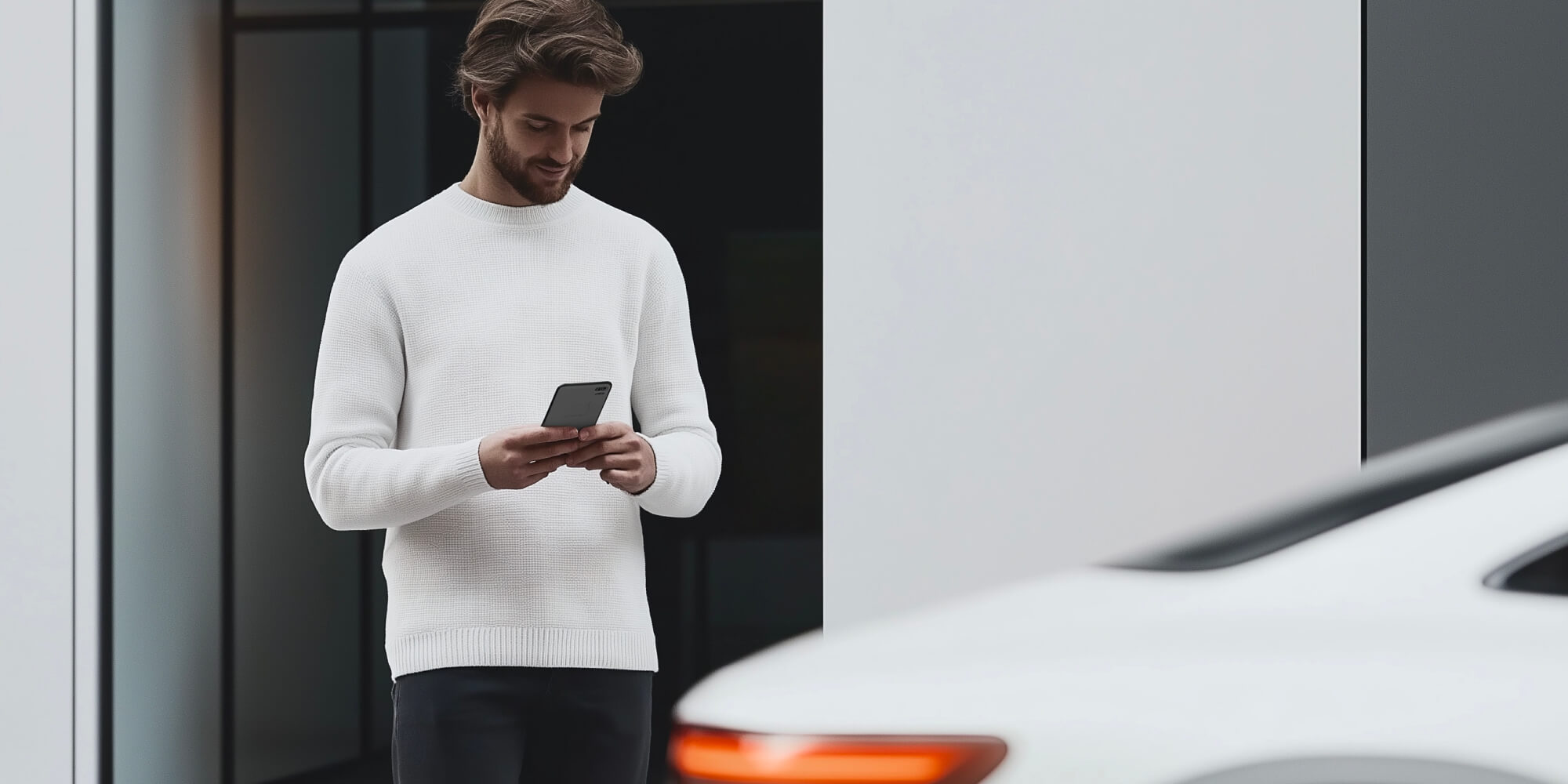 Man using his smartphone, standing near a car 