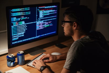 Young programmer coding on computer in the evening at home.