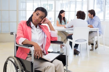 Woman with disability frowning with coworkers are in background in the office-1