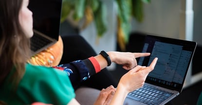 two women pointing at a laptop screen