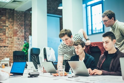 four software developers looking at laptops