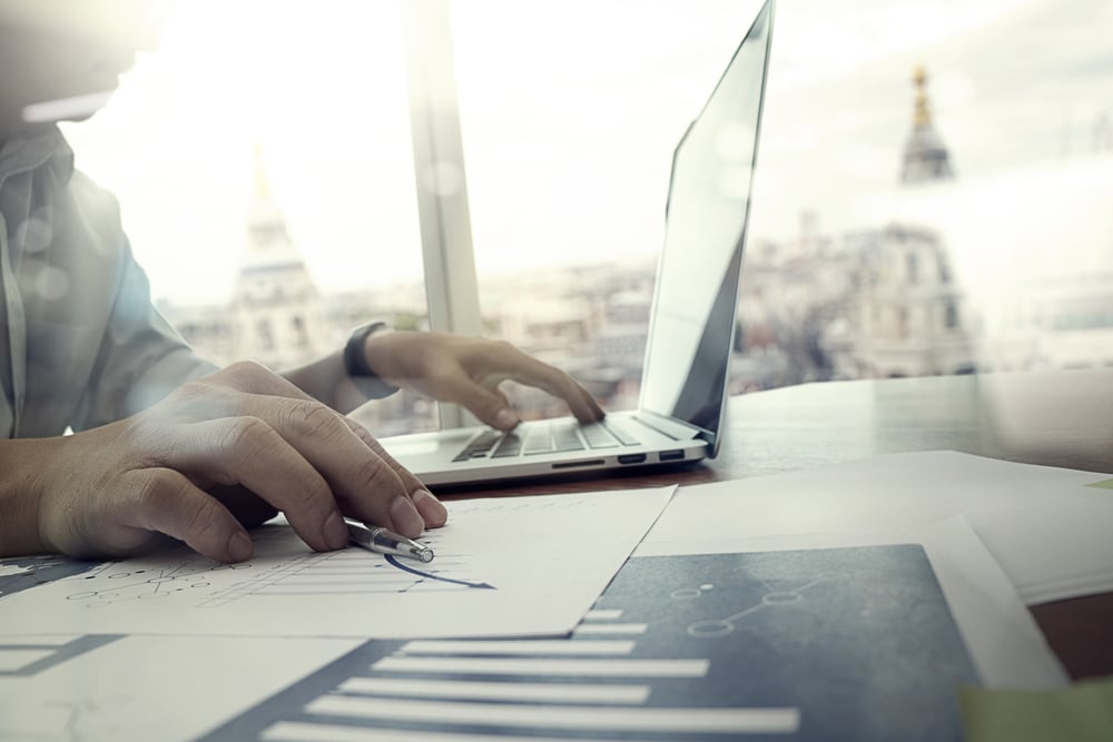 business documents on office table with laptop computer and graph financial diagram and man working in the background-2